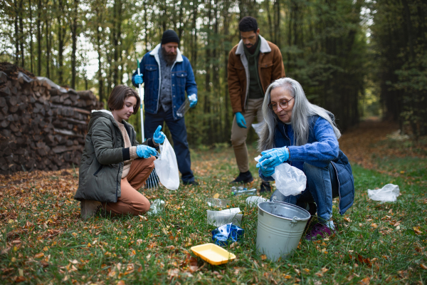 A group of volunteers cleaning up forest from waste, community service concept