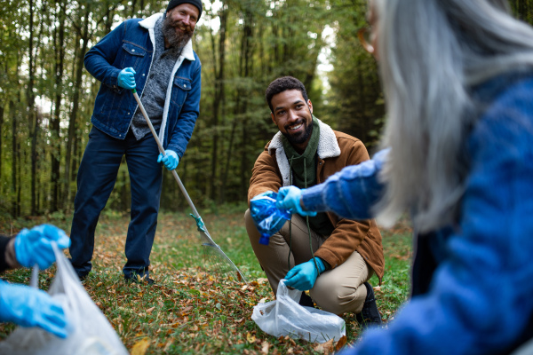 A diverse group of happy volunteers cleaning up forest from waste, community service concept.