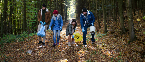 A diverse group of happy volunteers cleaning up forest from waste, community service concept.