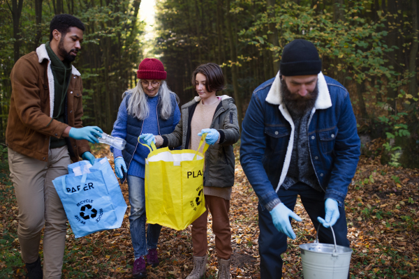 A diverse group of volunteers cleaning up forest from waste, community service concept