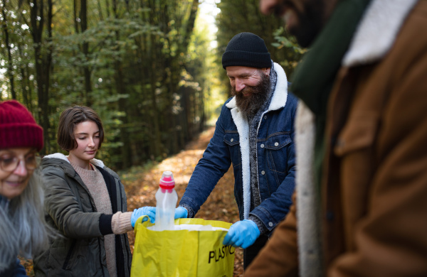 A diverse group of volunteers cleaning up forest from waste, community service concept