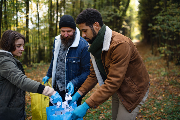 A diverse group of volunteers cleaning up forest from waste, community service concept.