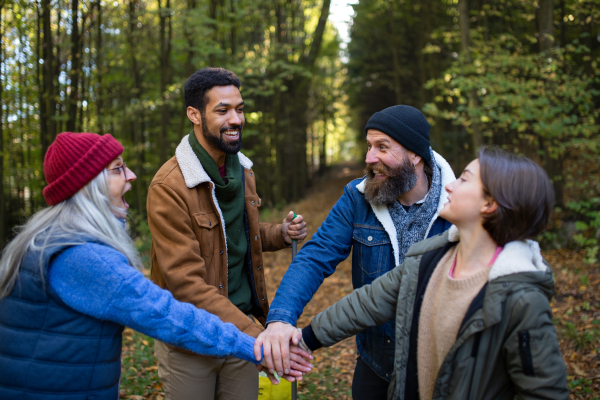 A diverse group of happy volunteers stacking hands together after cleaning up forest.