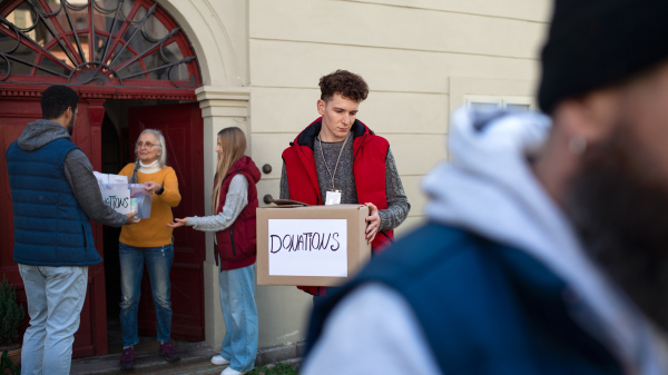 A diverse group of volunteers with donation boxes standing outdoors, social care and charity concept