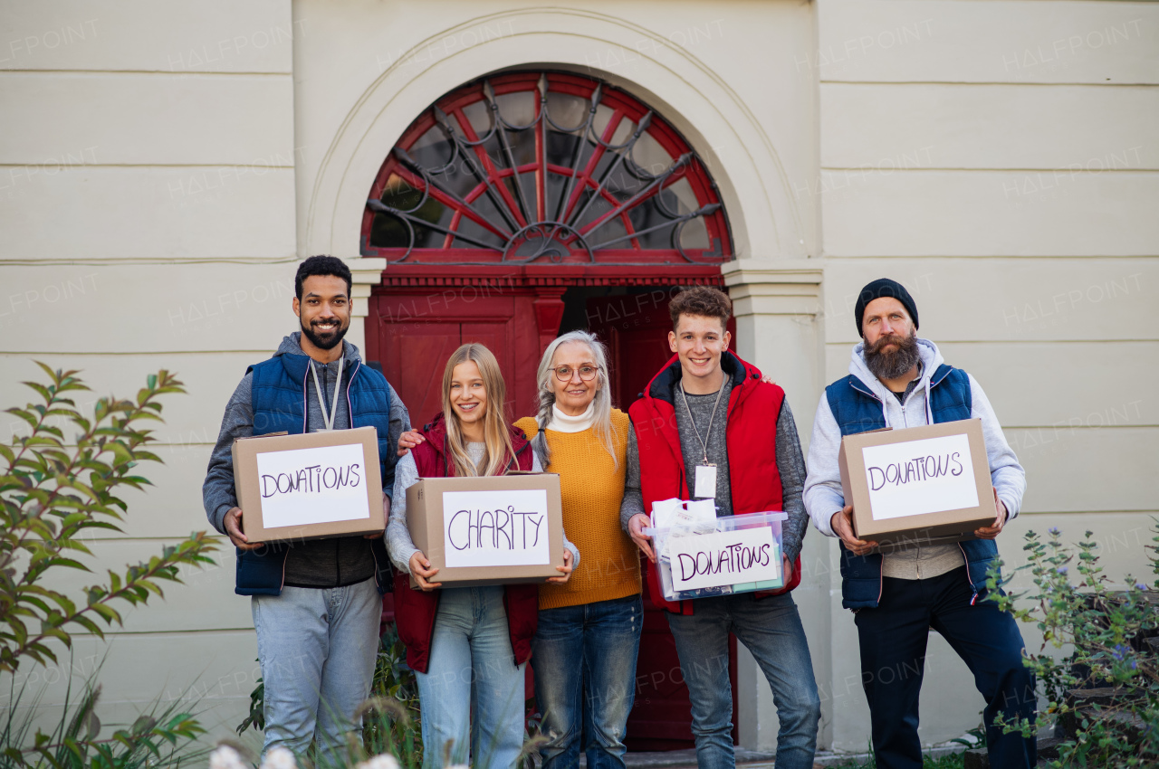 A diverse group of volunteers with donation boxes standing outdoors, social care and charity concept