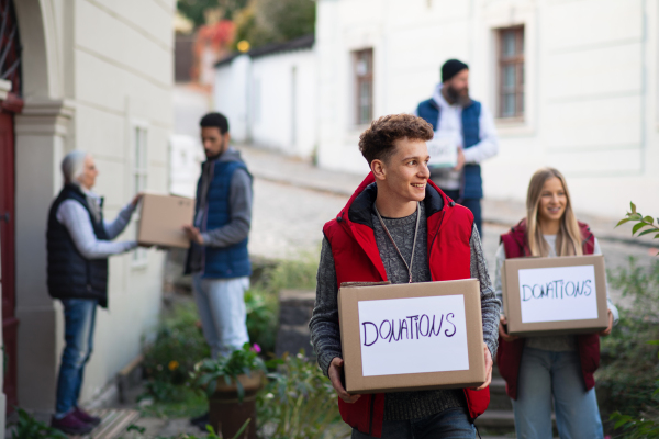 A diverse group of volunteers with donation boxes standing outdoors, social care and charity concept