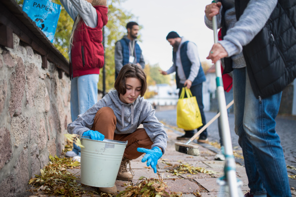 A diverse group of happy volunteers cleaning up street, community service concept