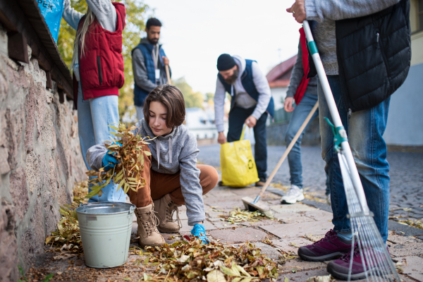 A diverse group of happy volunteers cleaning up street, community service concept