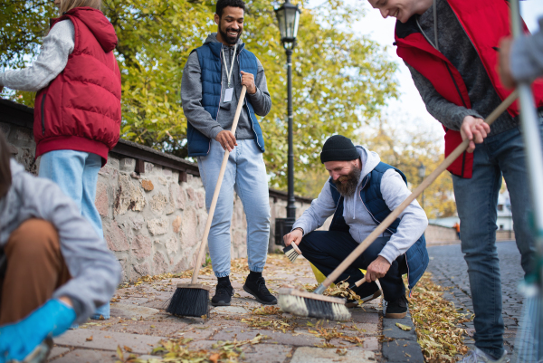 A diverse group of happy volunteers cleaning up street, community service concept