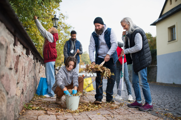 A diverse group of happy volunteers cleaning up street, community service concept