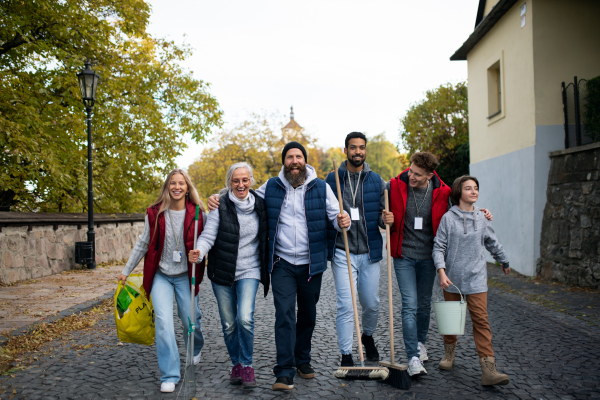 A diverse group of happy volunteers walking with tools to do street clean up, community service concept