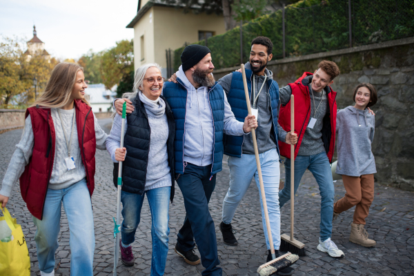 A diverse group of happy volunteers walking with tools to do street clean up, community service concept