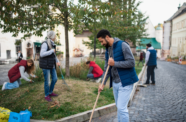 A young man volunteer with team cleaning up street, community service concept