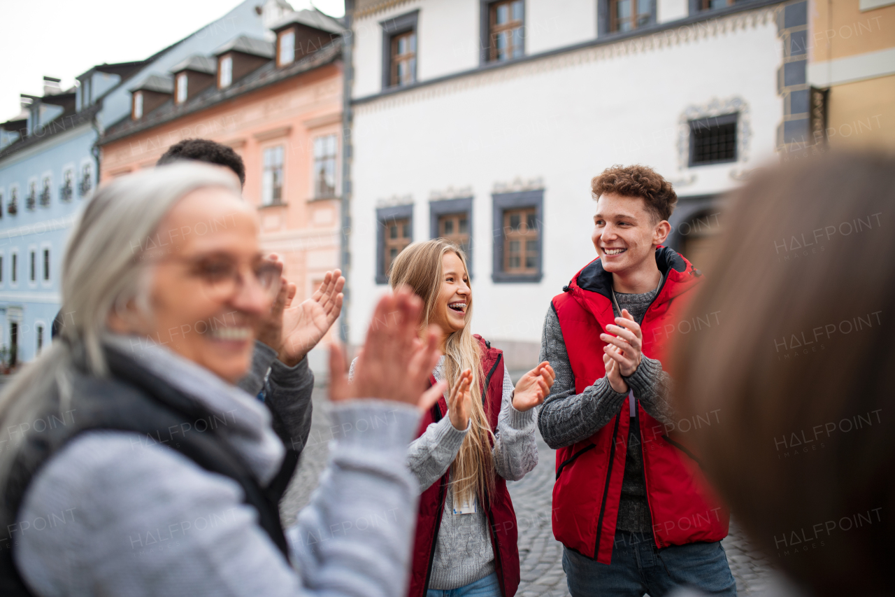 A diverse group of happy community service volunteers raising hands together outdoors in street