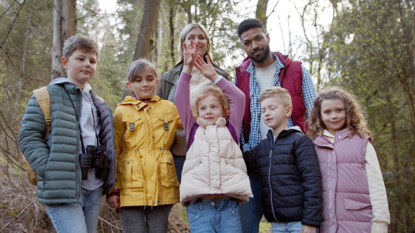 Teachers with group of small children outdoors in nature, looking at camera. Learning group education concept.