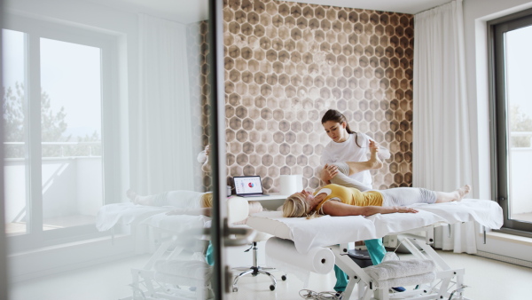 A senior woman having a yoga therapy with female therapist.