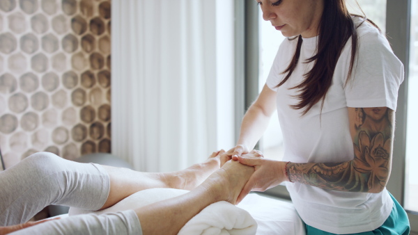 Unrecognizable senior woman having a yoga therapy with female therapist.