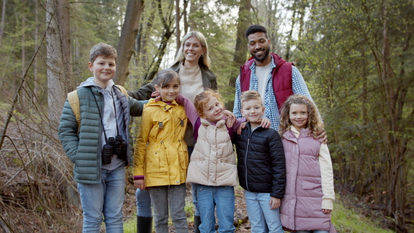 Teachers with group of small children outdoors in nature, looking at camera. Learning group education concept.