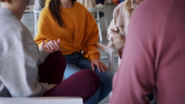 A group of people on therapy session, members holding each other by hand.