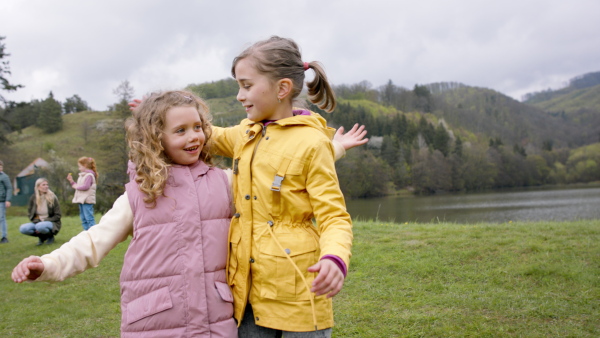 A small girls outdoors in nature, giving high five, hugging and looking at camera. Learning group education concept.