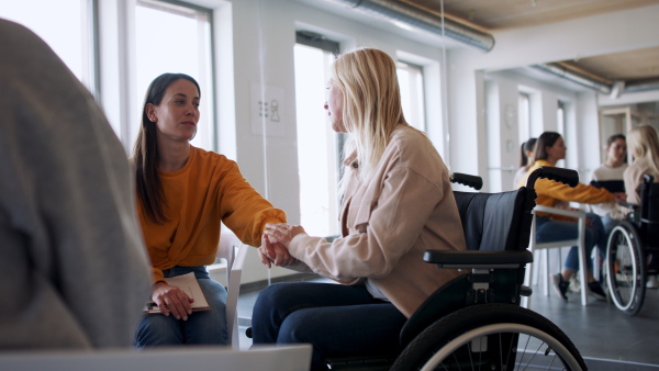 A group of people on therapy session, senior woman on wheelchair getting upset.