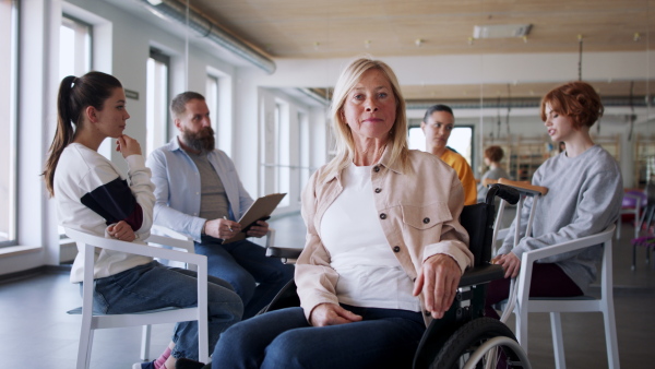 A group of people on therapy session, senior woman looking at camera. Coronavirus concept.