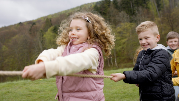 A group of school children doing rope pulling outside in nature.