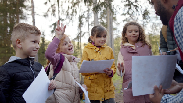 An african-american teachers with group of small children outdoors in nature, learning group education concept.