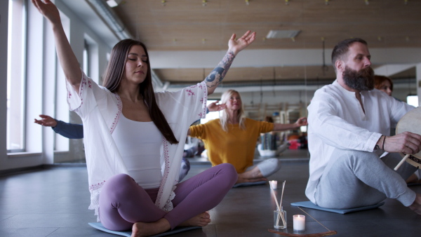 A group of people doing yoga exercises and meditating with candles.