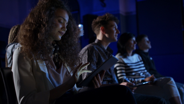 A group of people making notes while listening to presentation at conference.