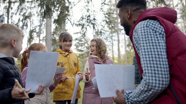 An african-american teachers with group of small children outdoors in nature, learning group education concept.