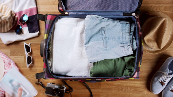 Top view of young woman packing for trip holiday, desktop travel concept.