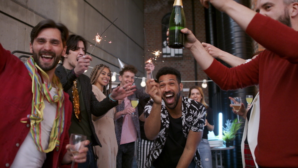 A large group of colleagues having a big party in office, opening champagne.