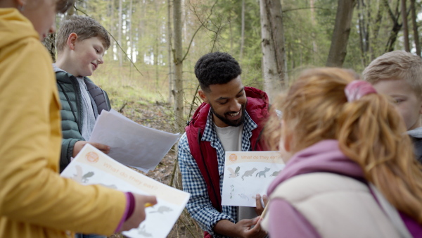 An african-american teachers with group of small children outdoors in nature, learning group education concept.