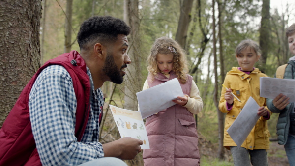 An african-american teachers with group of small children outdoors in nature, learning group education concept.