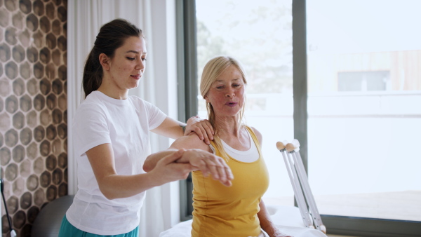 A senior woman having a yoga therapy with female therapist.