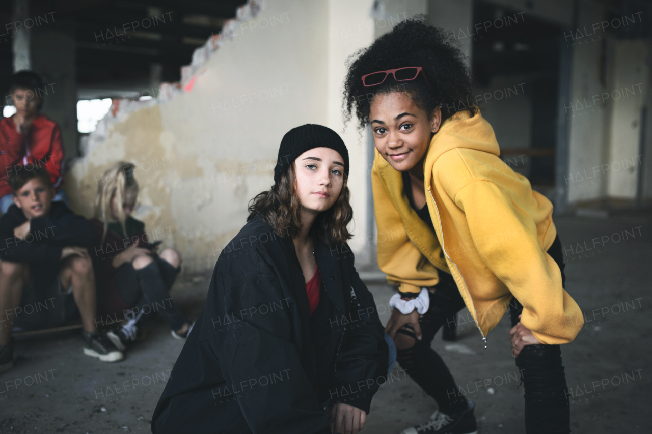 Front view of group of teenagers girl gang standing indoors in abandoned building, hanging out.