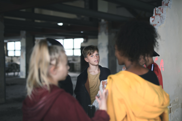 Group of teenagers gang standing indoors in an abandoned building, talking.