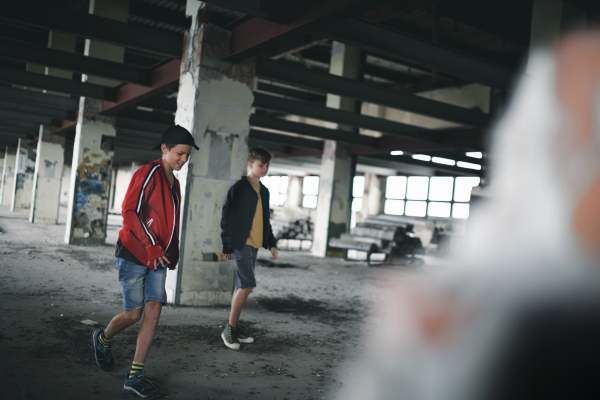 Two teenagers boys gang indoors in abandoned building, walking and talking.