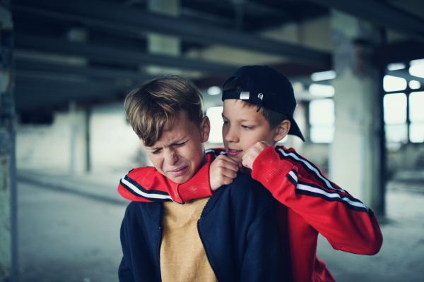 Teenage boy attacked by thug indoors in abandoned building, gang violence and bullying concept.