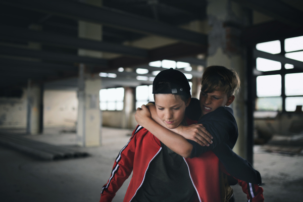 Teenage boy attacked by thug indoors in abandoned building, gang violence and bullying concept.