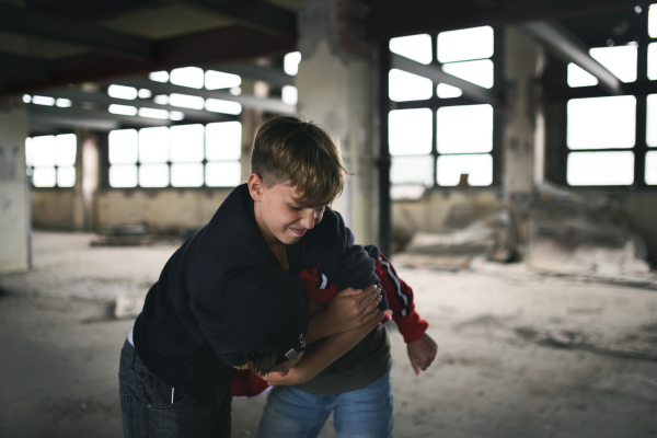 Teenage boy attacked by thug indoors in abandoned building, gang violence and bullying concept.