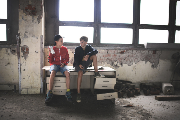 Group of teenagers boys gang indoors in abandoned building, talking.