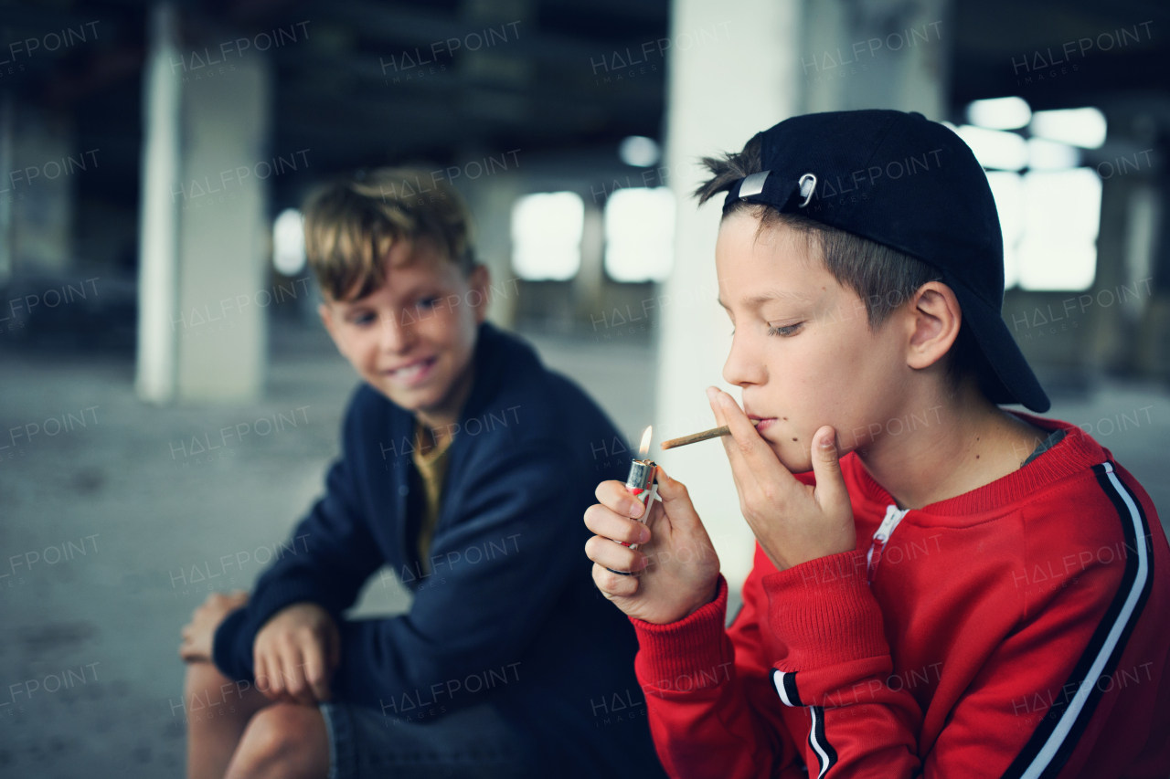 Group of teenagers boys gang indoors in abandoned building, smoking cigarettes.