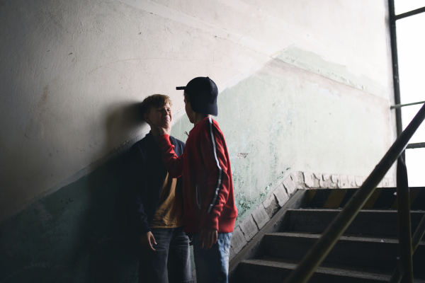 Teenage boy attacked by thug indoors in abandoned building, gang violence and bullying concept.