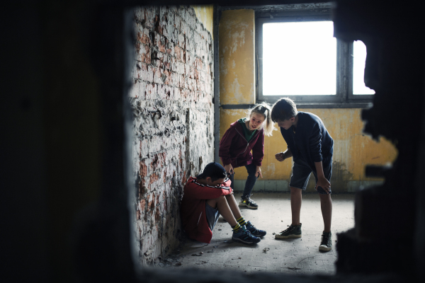 Teenage boy attacked by thugs indoors in abandoned building, gang violence and bullying concept.