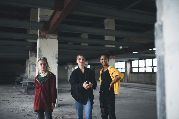 Group of teenagers girl gang standing indoors in abandoned building, hanging out.