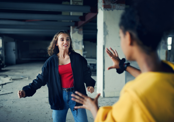 Scared teenage girl attacked by thugs in abandoned building, gang violence and bullying concept.