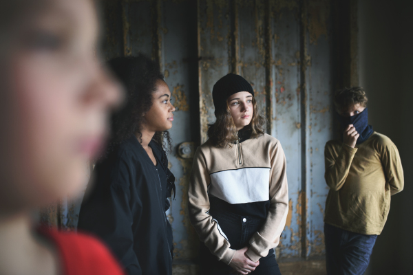 Front view of group of teenagers gang standing indoors in abandoned building, bullying concept.