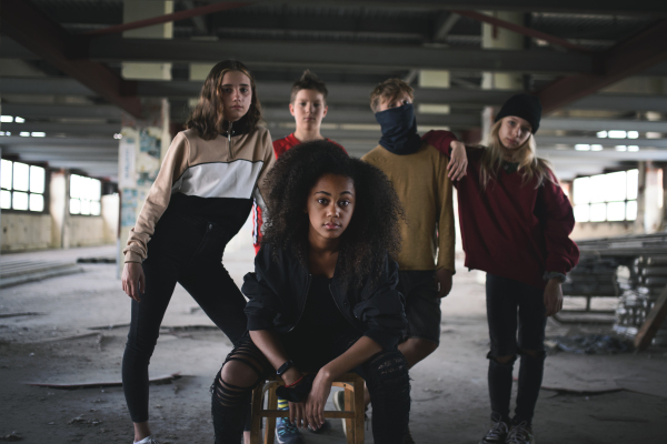 Front view of group of teenagers gang standing indoors in abandoned building, bullying concept.